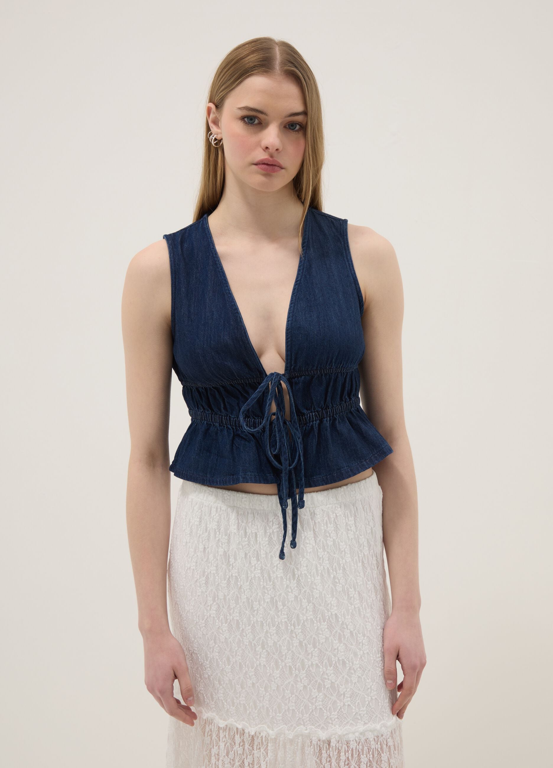 Blue sleeveless denim blouse in pure cotton, slim fit with tie fastening